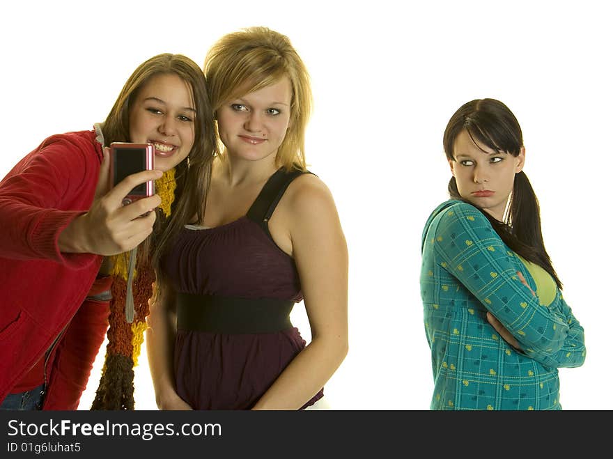 Two girls take photos with cell phone while leaving out a third girl. Two girls take photos with cell phone while leaving out a third girl