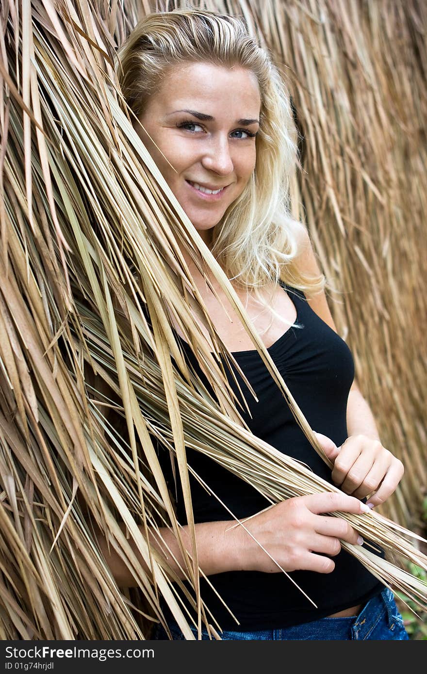 Beautiful blonde girl standing at straw wall. Beautiful blonde girl standing at straw wall