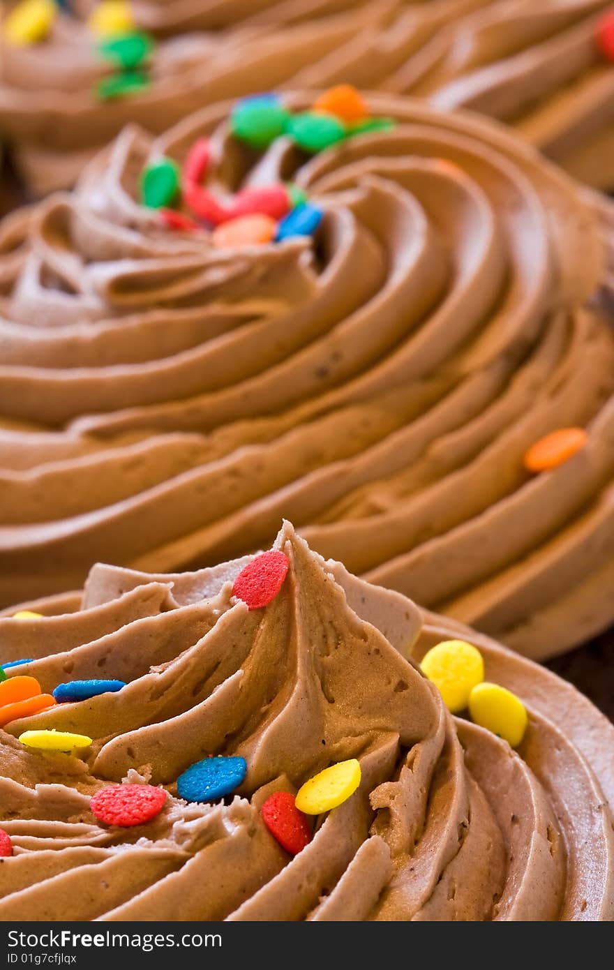 Freshly baked cupcakes close up with colored candies on the frosting