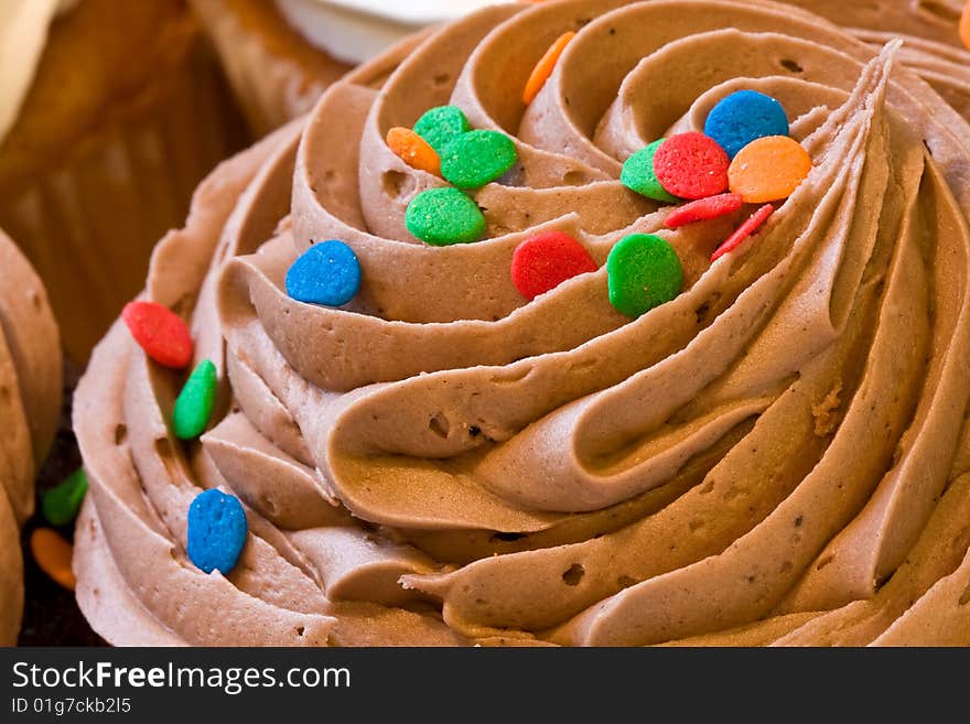 Freshly baked cupcakes close up with colored candies on the frosting