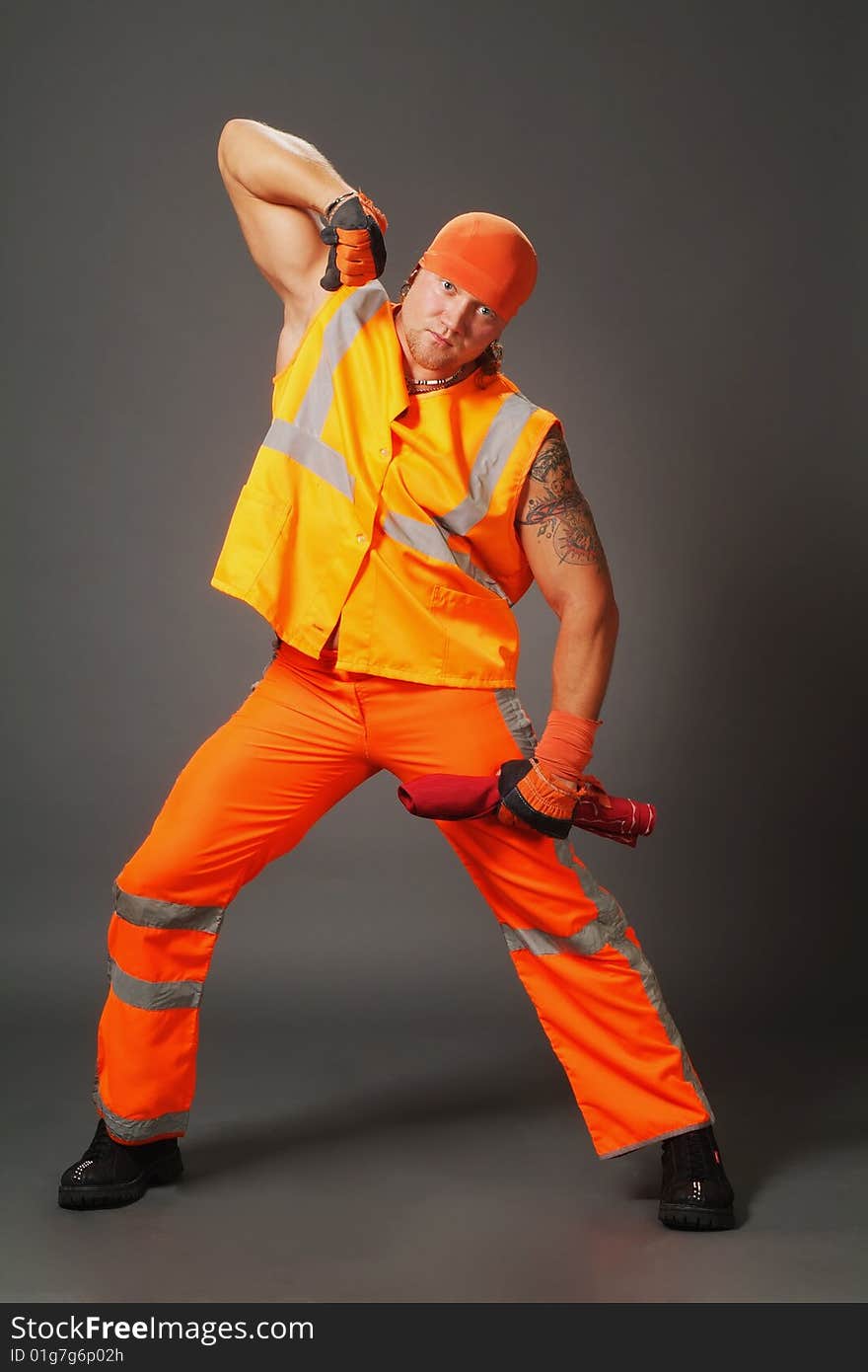 The worker in orange clothes on a grey background in studio. The worker in orange clothes on a grey background in studio