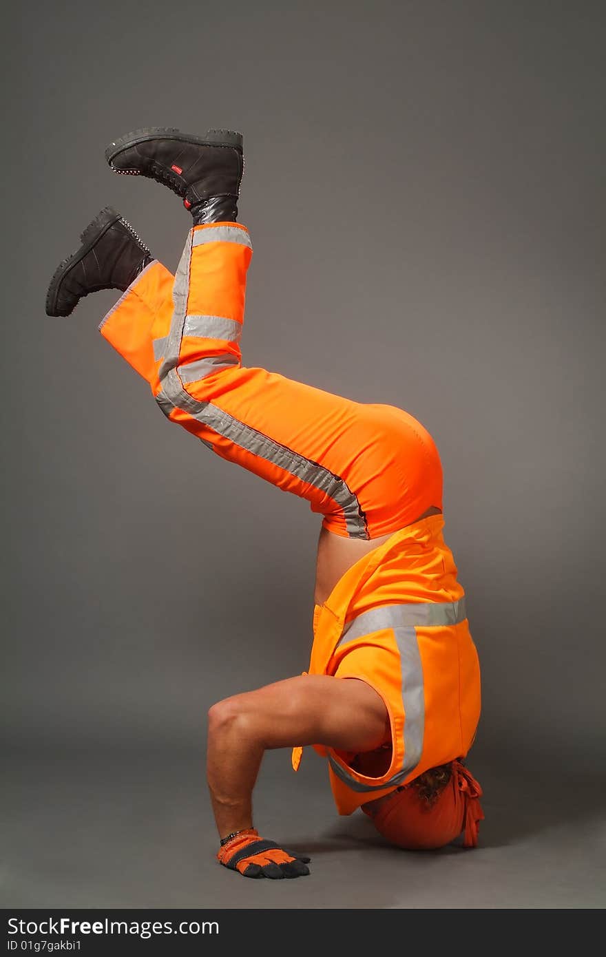 The worker in orange clothes on a grey background in studio. The worker in orange clothes on a grey background in studio