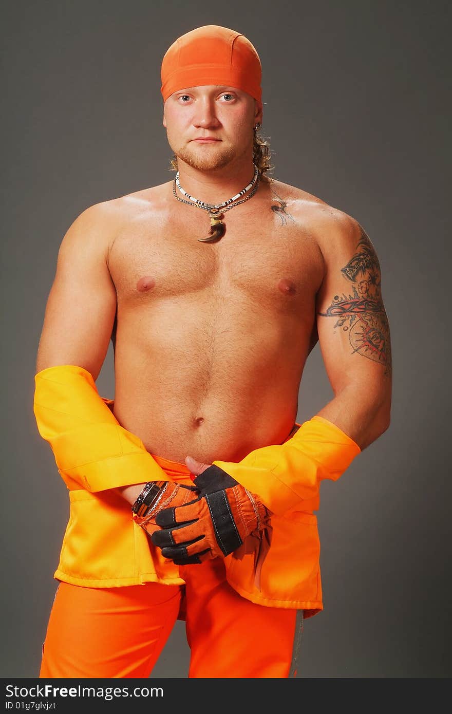 The worker in orange clothes on a grey background in studio. The worker in orange clothes on a grey background in studio