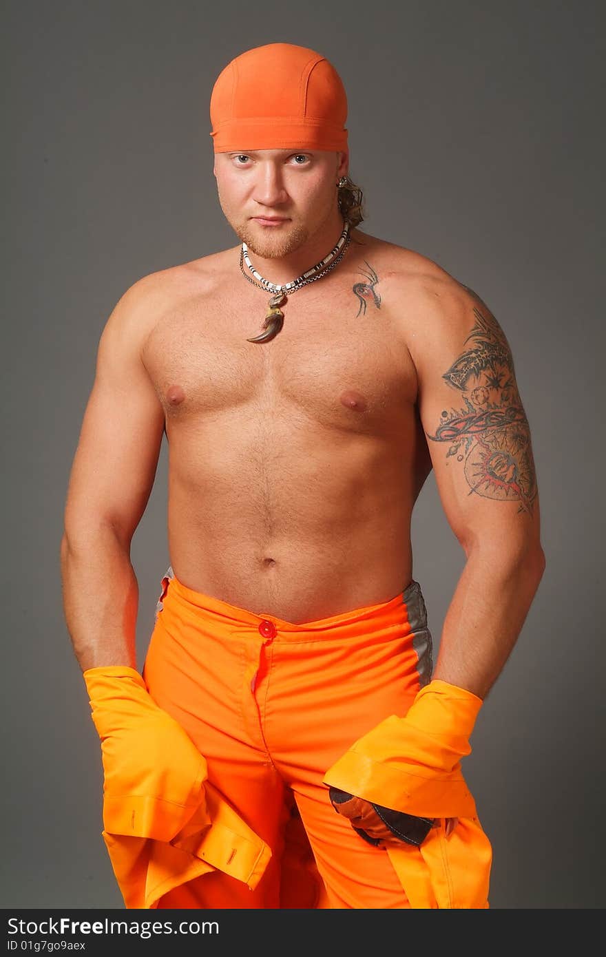 The worker in orange clothes on a grey background in studio. The worker in orange clothes on a grey background in studio