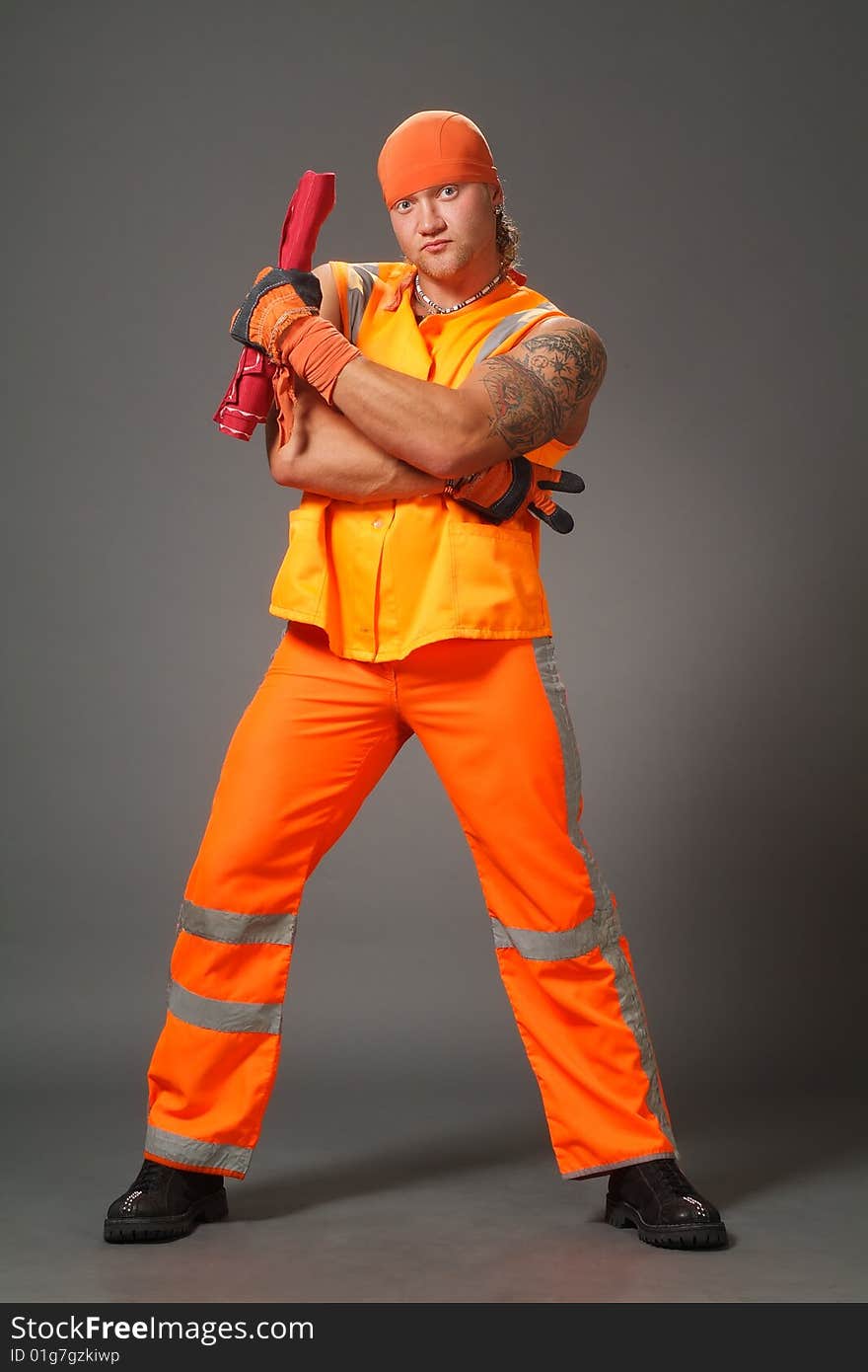 The worker in orange clothes on a grey background in studio. The worker in orange clothes on a grey background in studio