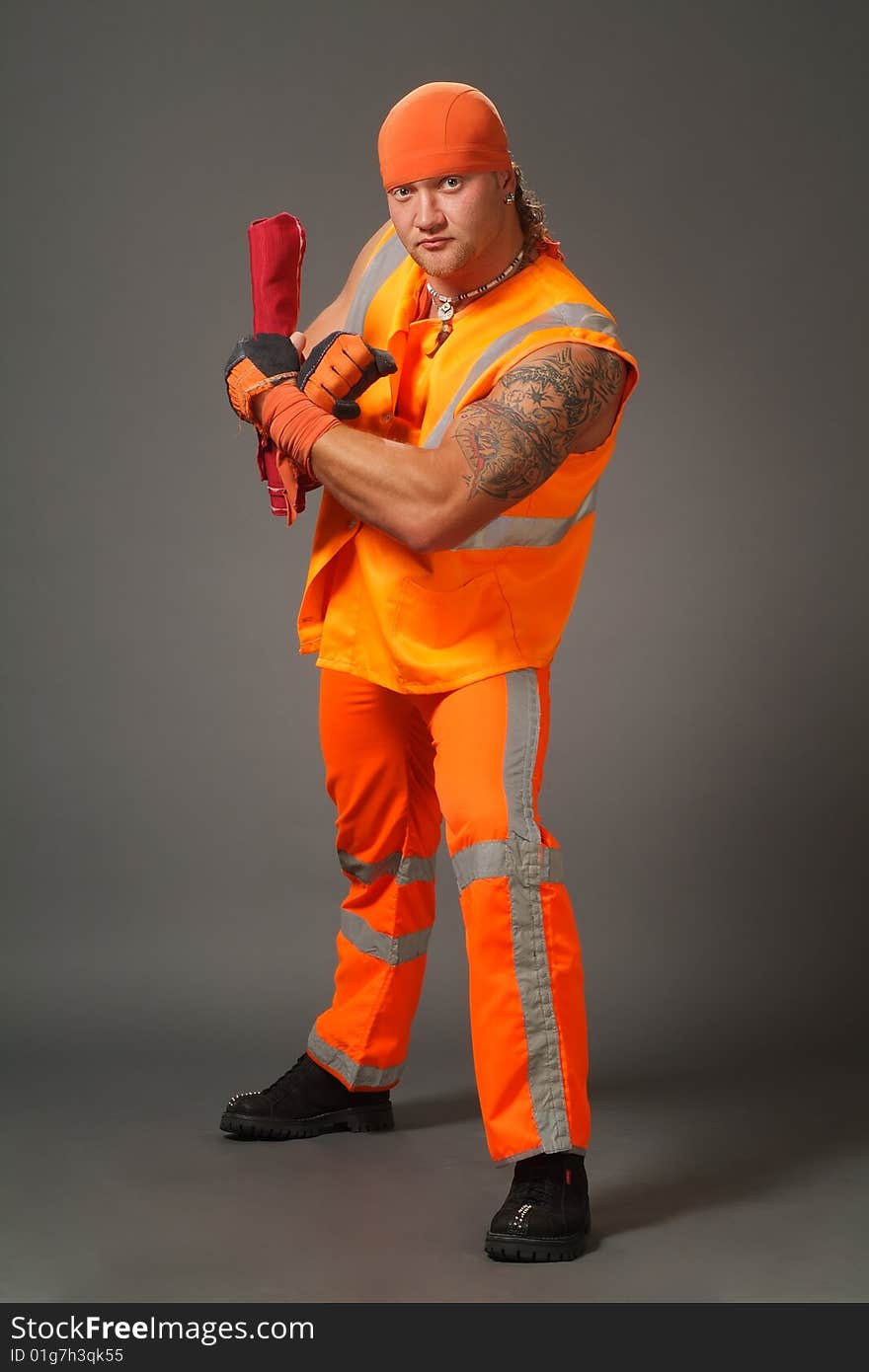 The worker in orange clothes on a grey background in studio. The worker in orange clothes on a grey background in studio