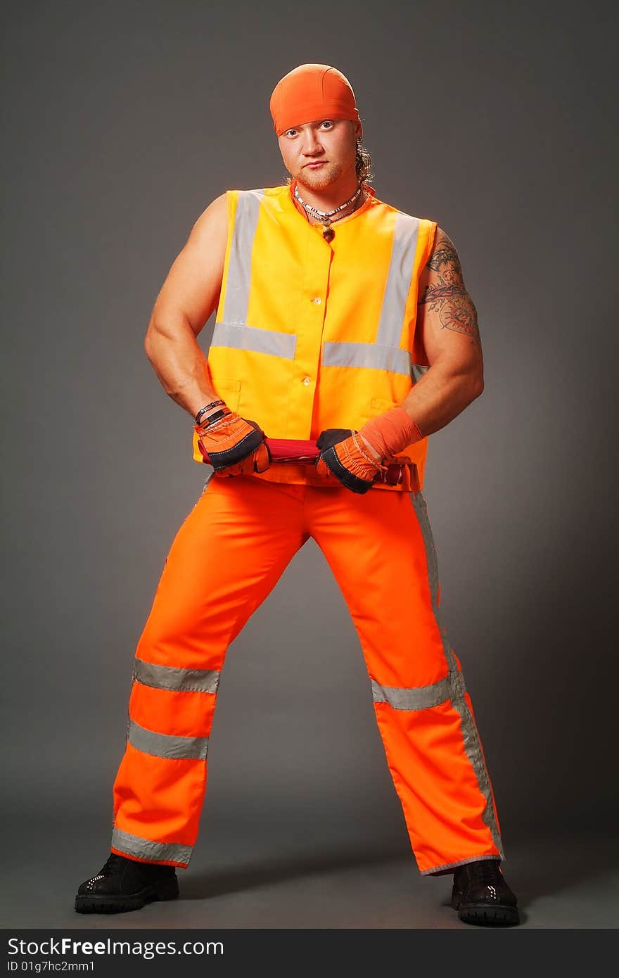 The worker in orange clothes on a grey background in studio. The worker in orange clothes on a grey background in studio