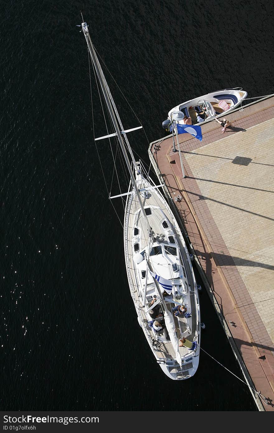 Sailboat and motorboat moored to a pier on sunny summer day.