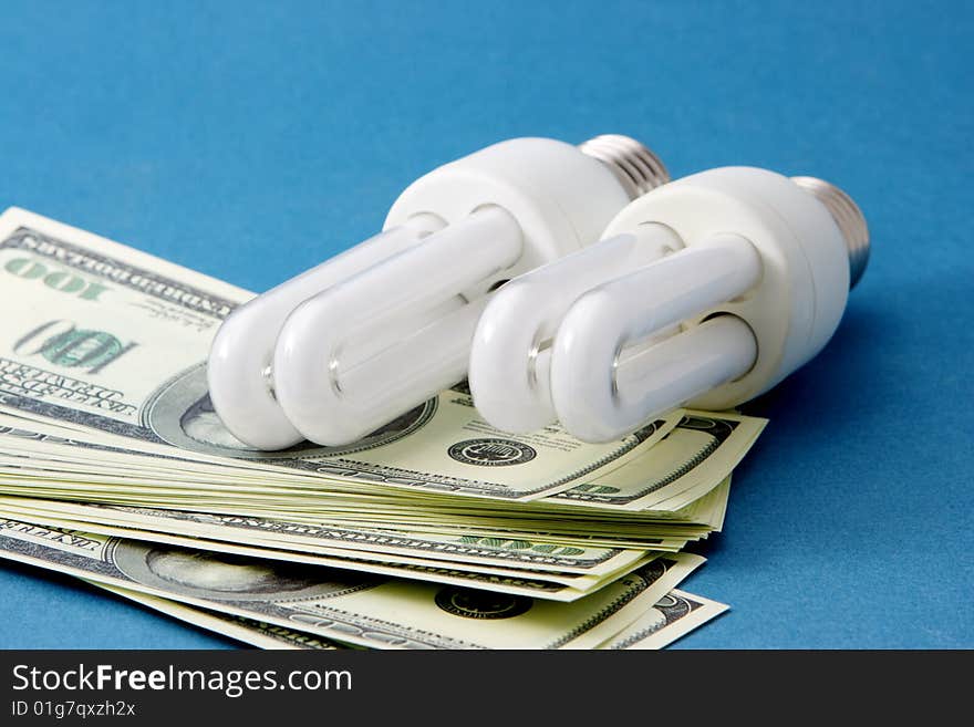 Energy saving light bulb on a pile of money. Energy saving light bulb on a pile of money