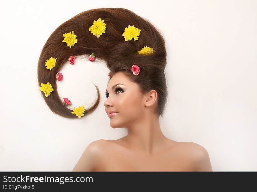 Attractive young woman with flowing hair and flowers on white background