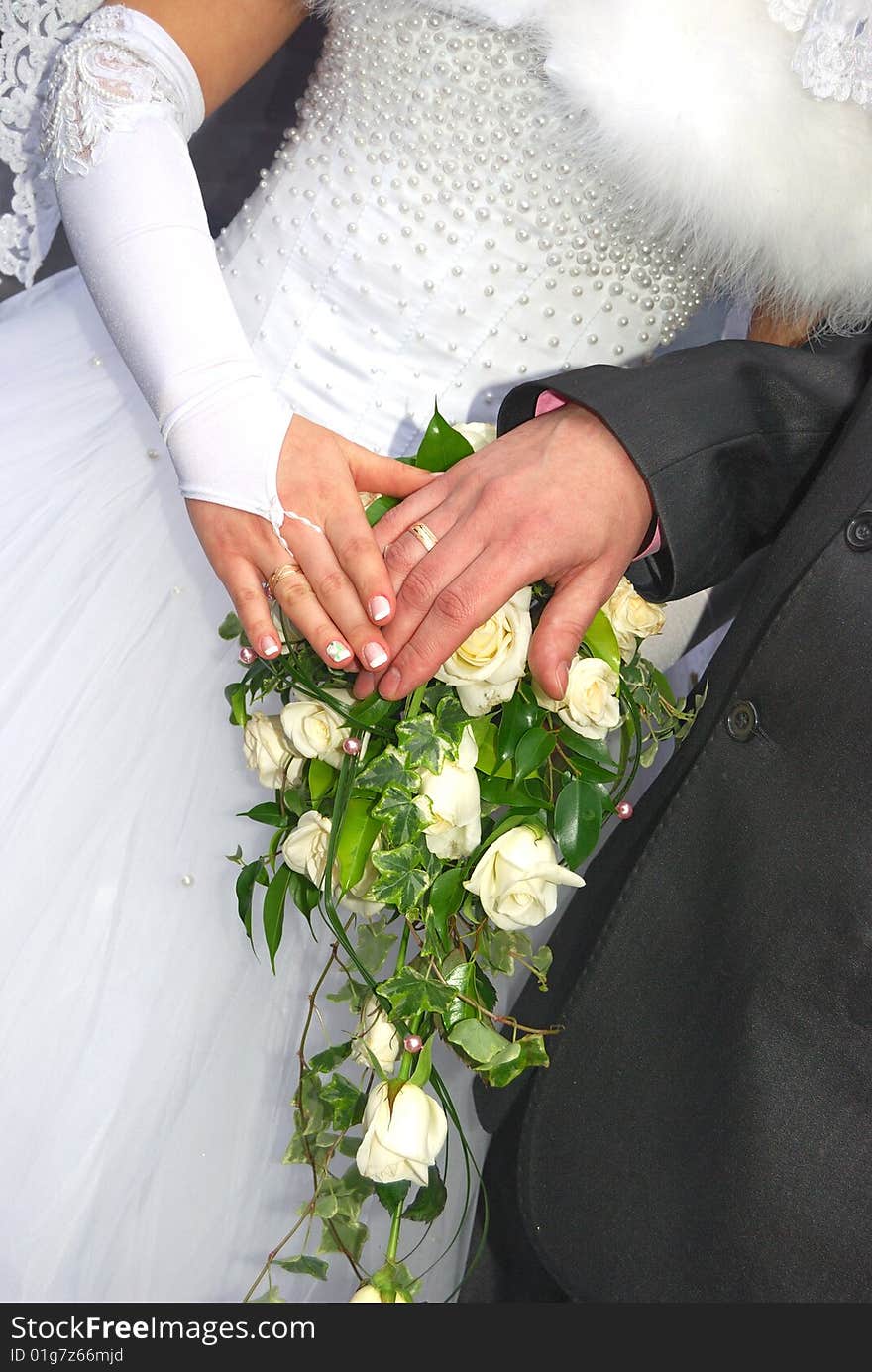 A bride holds her bouquet of pink roses with two hands, wedding ring in view. A bride holds her bouquet of pink roses with two hands, wedding ring in view