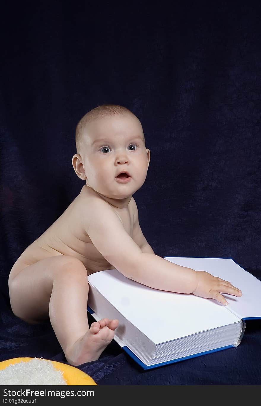 Child sits with book on turn blue background. Child sits with book on turn blue background