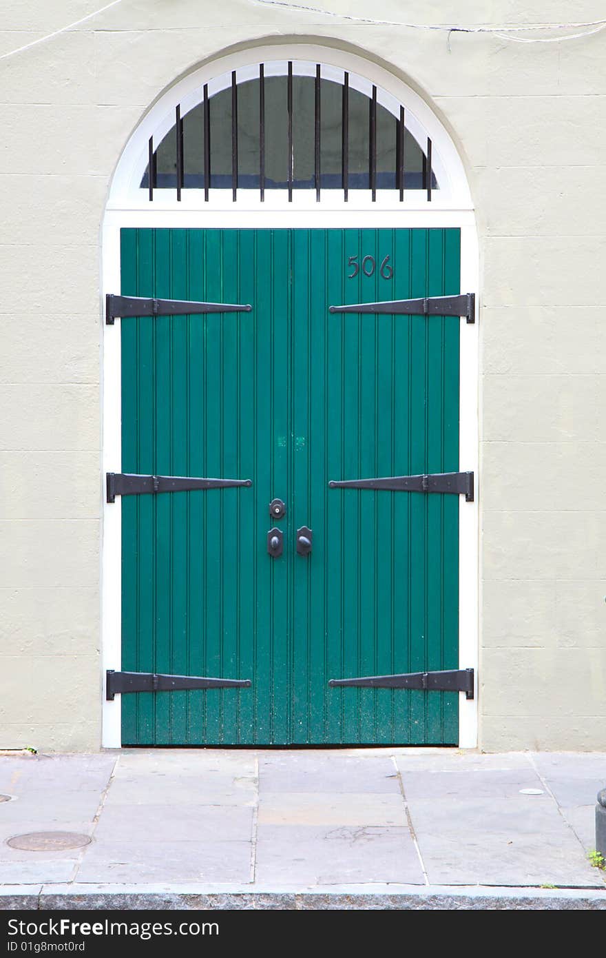 Arched doorway with green doors and antique hinges, in vertical orientation