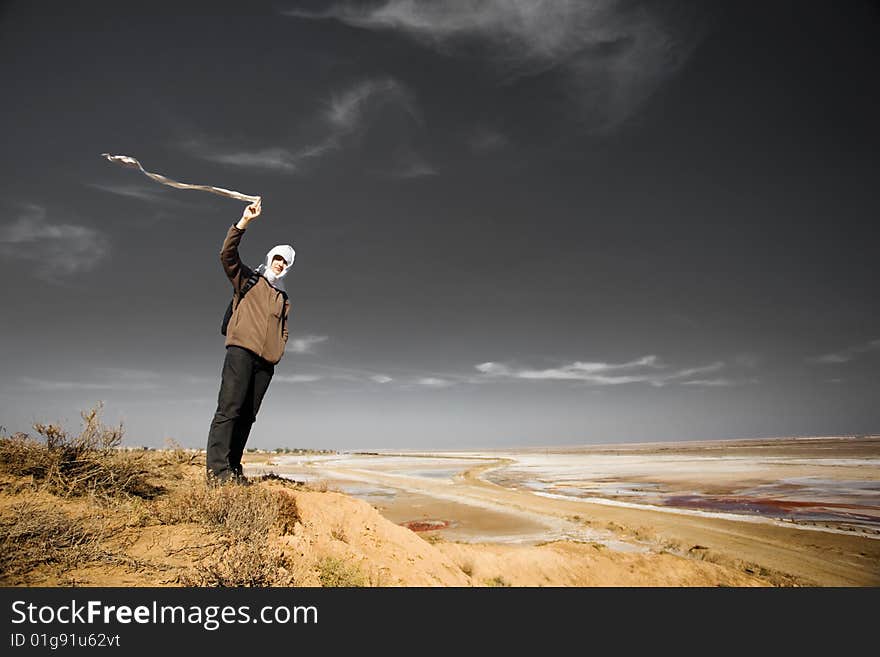 Man with a white cloth on the bank of a dry lake