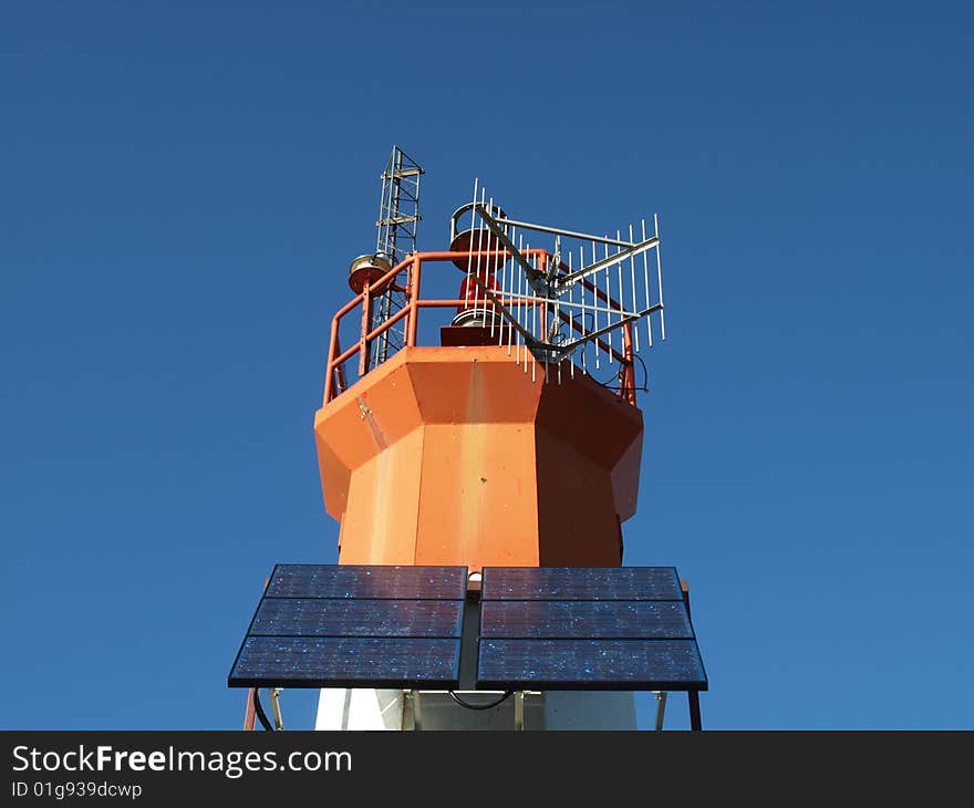 A lighthouse is equipped with solar power panels on a clear blue sky day. A lighthouse is equipped with solar power panels on a clear blue sky day.