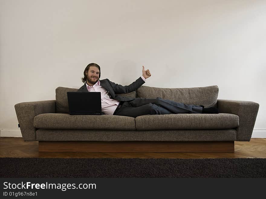 Businessman lies on the sofa and doin thumbs up