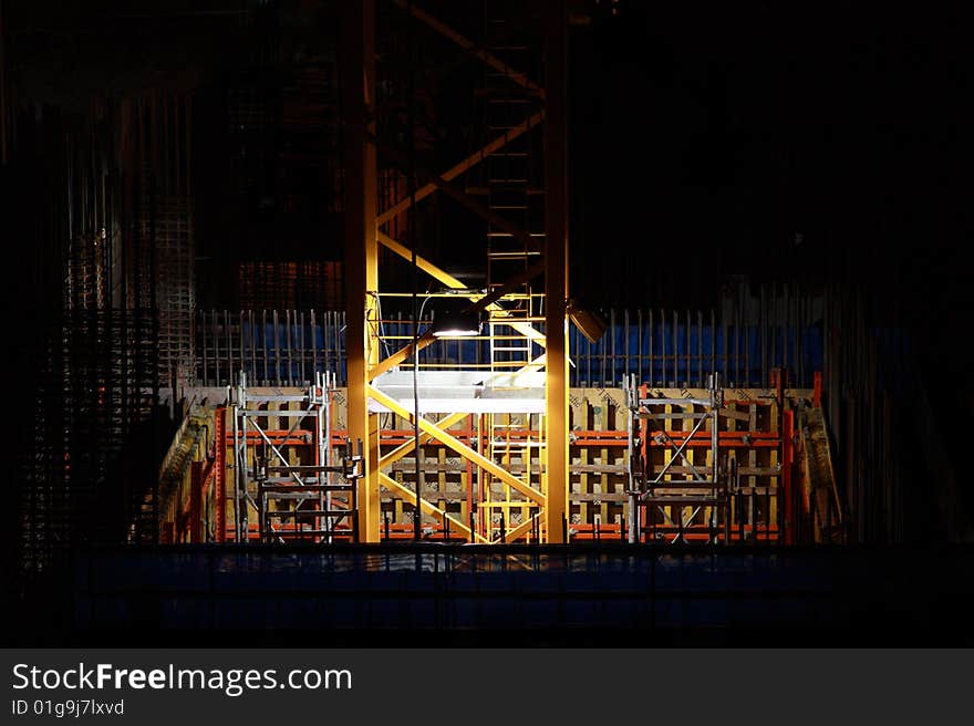 Construction site at night illuminated by to lights on crane tower. Construction site at night illuminated by to lights on crane tower