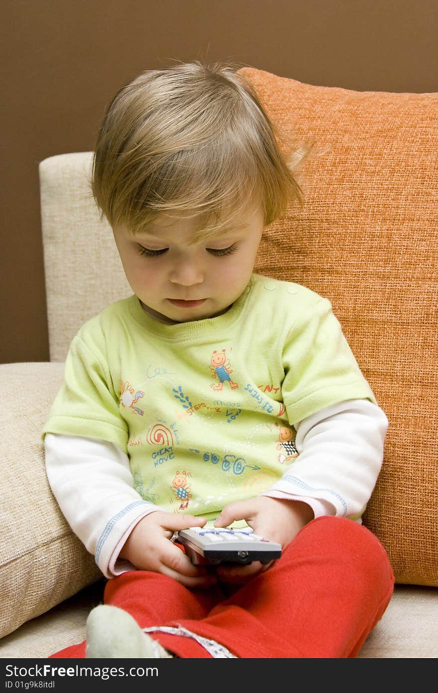 Sweet baby girl with remote control on sofa