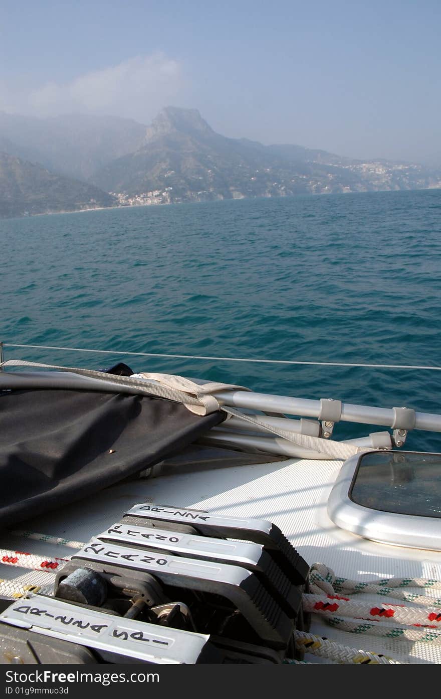 Detail of clam cleat on deck of a sailing boat in the mediterranean sea; on the ground a view of the amalfitan coast