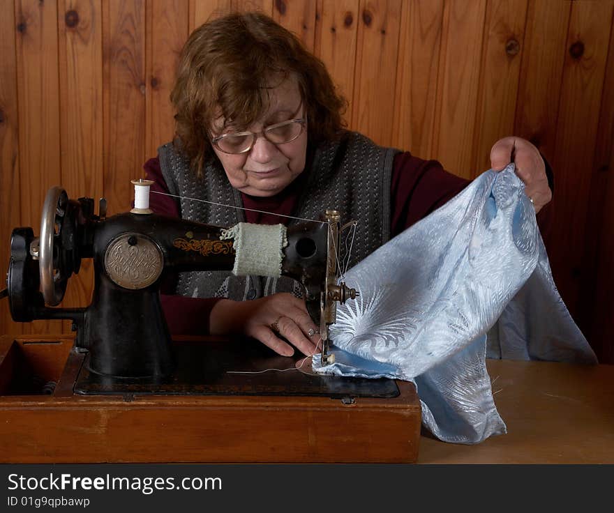 The old woman sews on the sewing machine