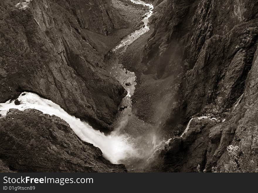 Voringfossen waterfall is Norway's most famous waterfall. It situated at the edge of Hardangervidda, near Eidfjord. The water falls almost 200 meters. Sepia-toned picture. Voringfossen waterfall is Norway's most famous waterfall. It situated at the edge of Hardangervidda, near Eidfjord. The water falls almost 200 meters. Sepia-toned picture.