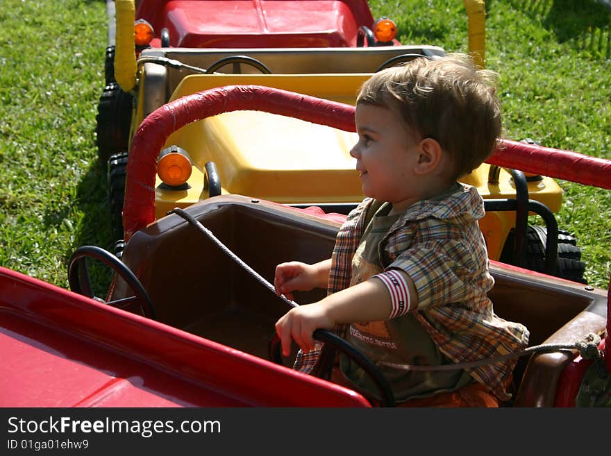 A toddler driving a car at an amusement park. A toddler driving a car at an amusement park.