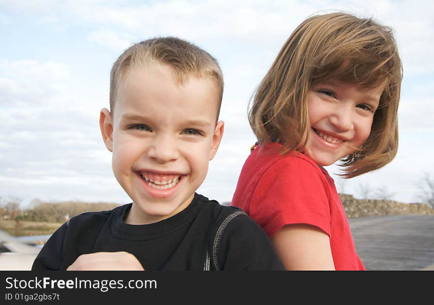 Two Children Smile for the Camera at the Park.