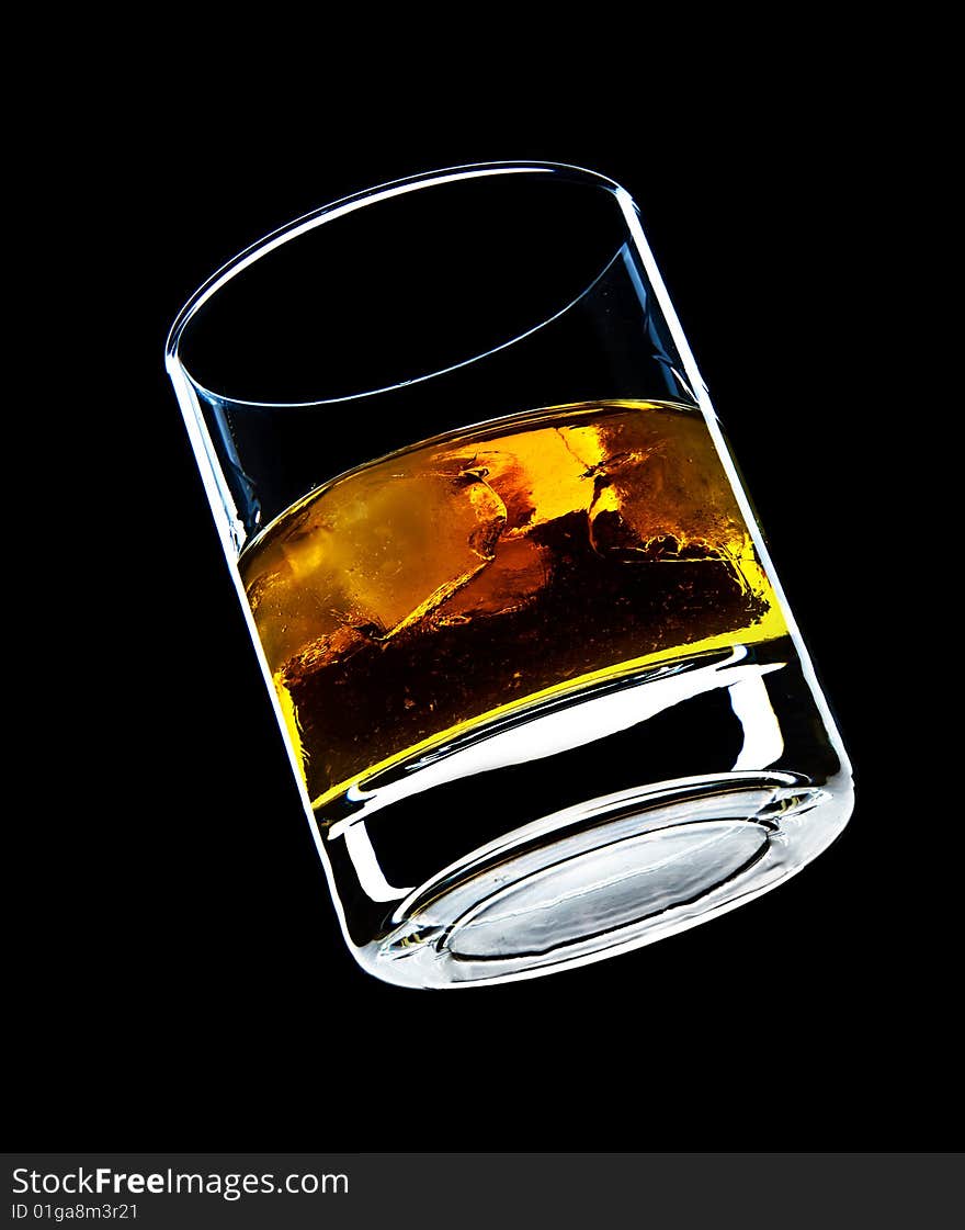 Glass of whiskey and ice isolated over a black background