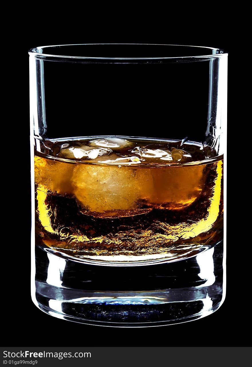 Glass of whiskey and ice isolated over a black background