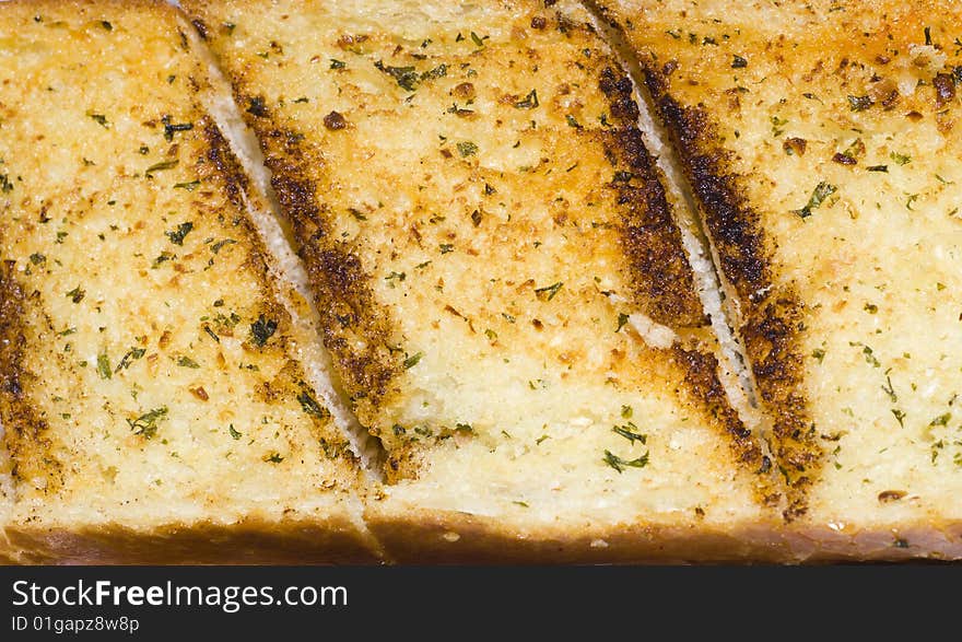 Slice of golden garlic bread with herbs. Slice of golden garlic bread with herbs.