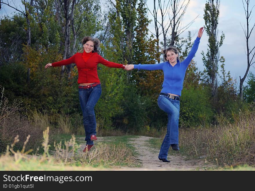 Two girlfriends run across the field having joined hands. Two girlfriends run across the field having joined hands