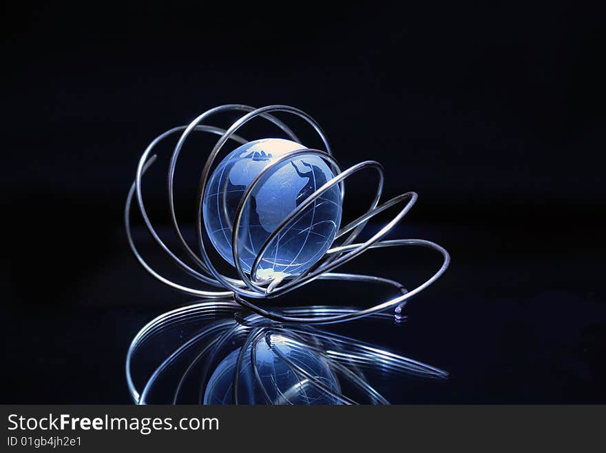 Glassy globe inside tangle made from wire on dark background. Glassy globe inside tangle made from wire on dark background