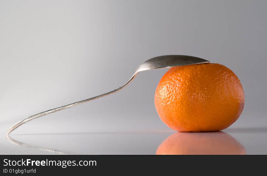 Copper teaspoon leaning a tangerine