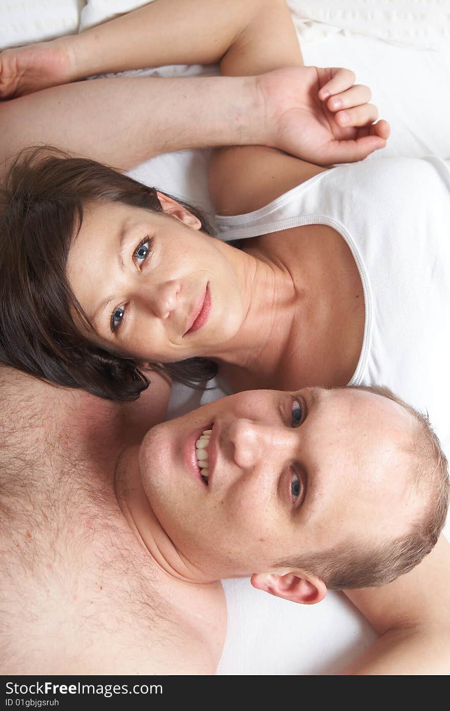 Portrait of young happy loving couple in their bedroom. Portrait of young happy loving couple in their bedroom.