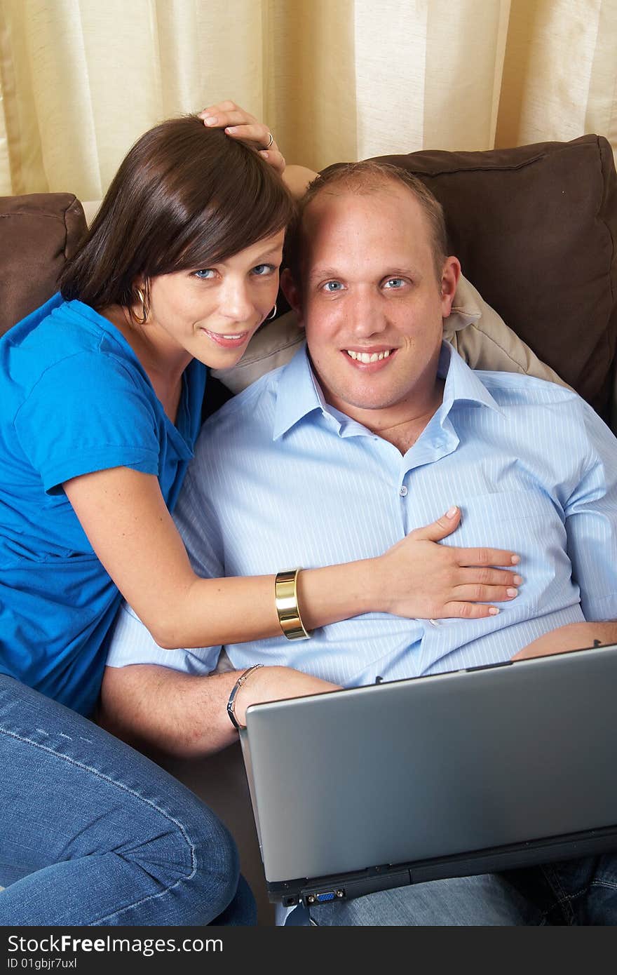 Young couple on the couch at home looking at the laptop!. Young couple on the couch at home looking at the laptop!