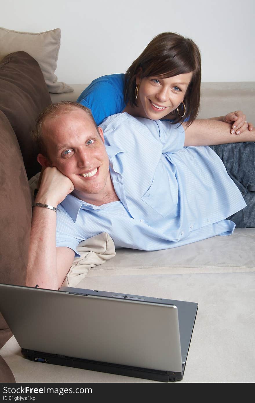 Young couple on the couch at home looking at the laptop!. Young couple on the couch at home looking at the laptop!