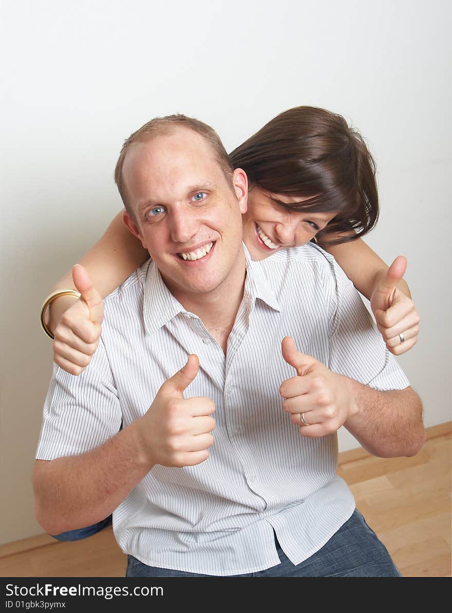 A young couple in love shows a thumbs up sign in their new appartment. A young couple in love shows a thumbs up sign in their new appartment.