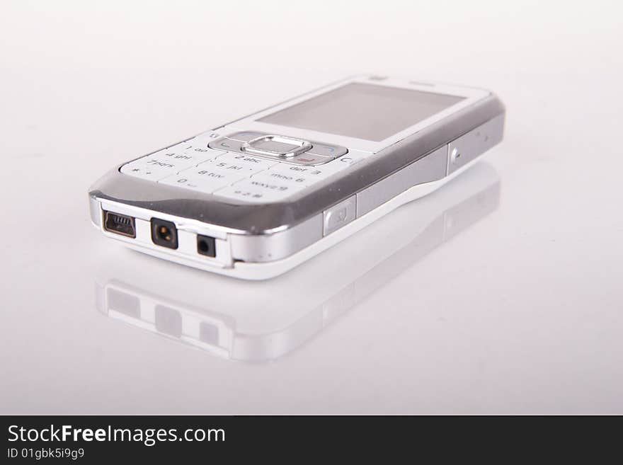 Isolated shot of a white cell phone. The phone is mirrored . Lot of copyspace. Isolated shot of a white cell phone. The phone is mirrored . Lot of copyspace.