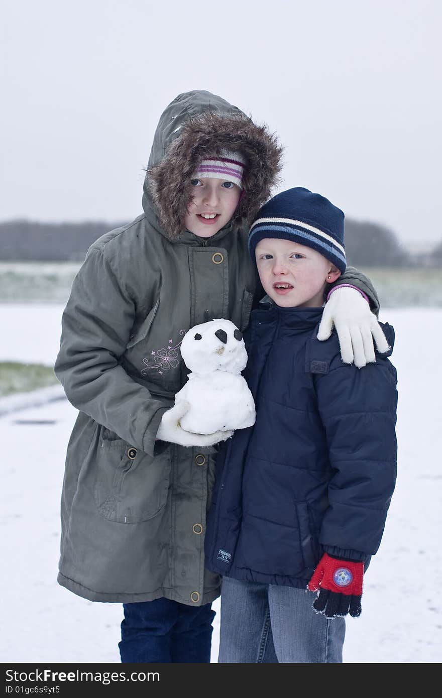 Brother and sister take a pause from playing in the snow