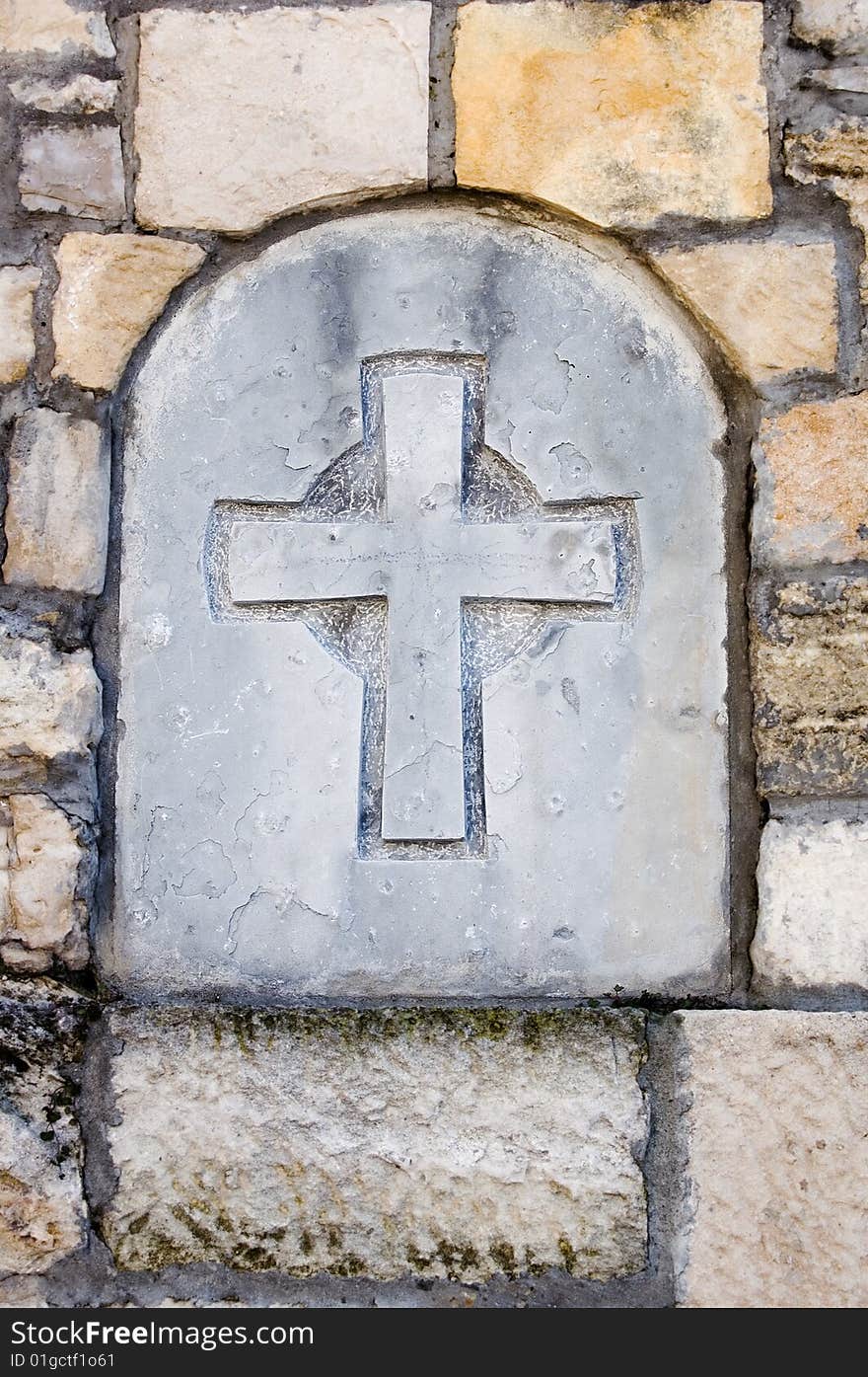 Stone cross built in old wall