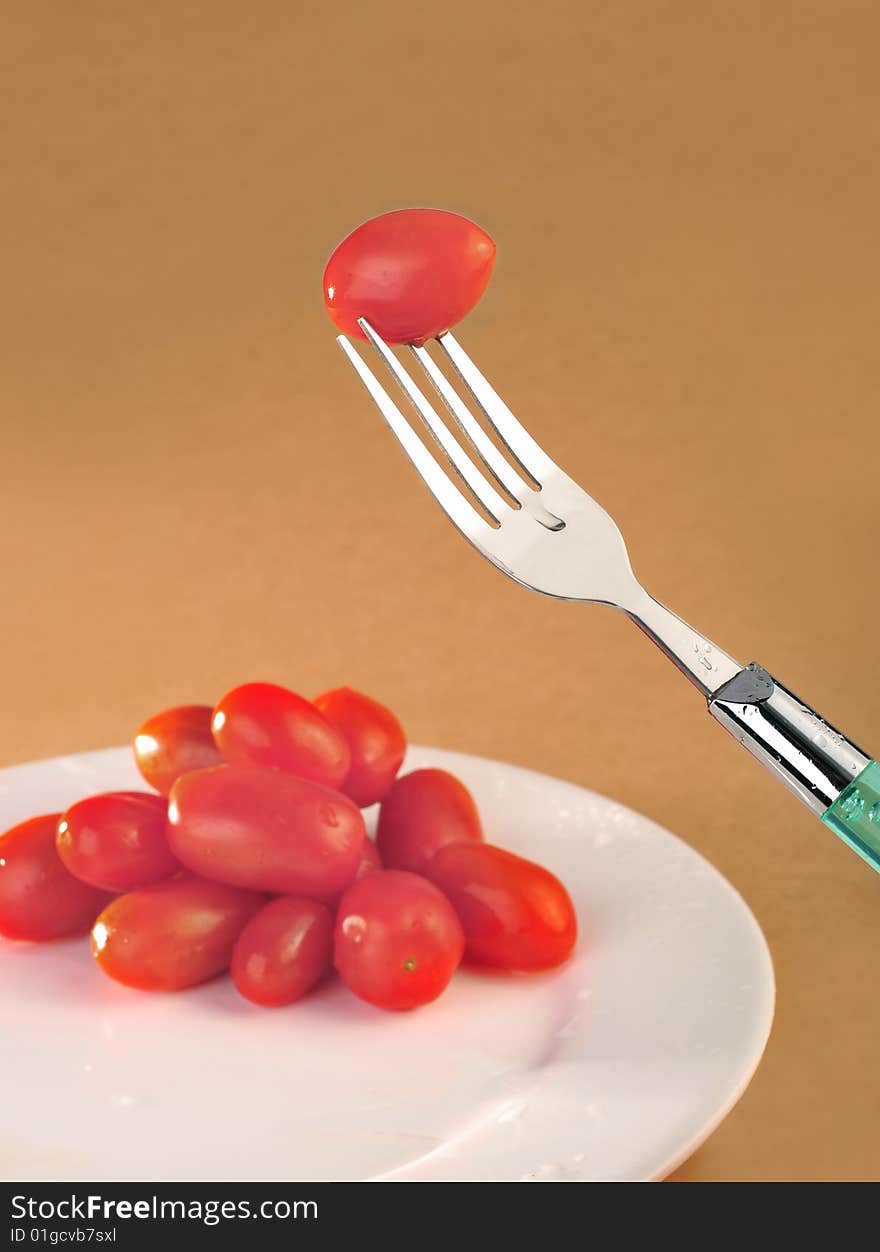 Fork small tomato in brown
background. Fork small tomato in brown
background