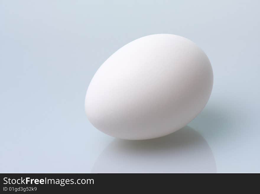 White egg rests on a blue table. White egg rests on a blue table.