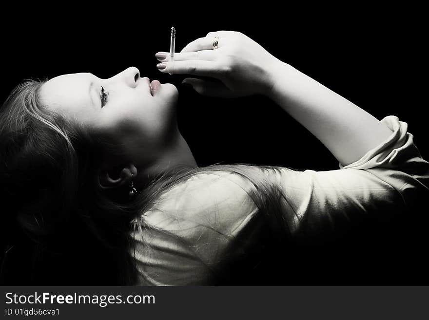 Portrait of beautiful young woman with a cigarette in a hand on a black background