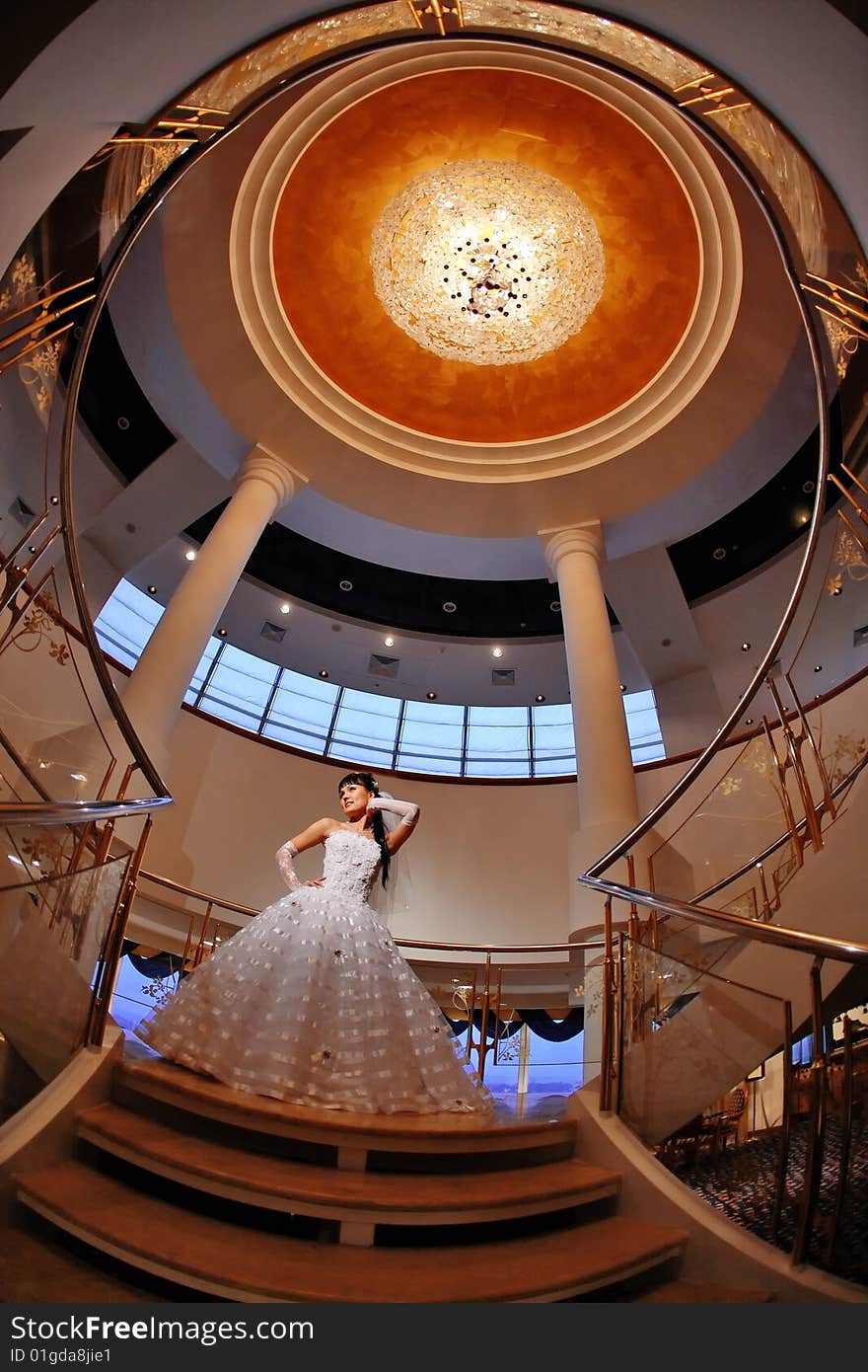 Bride on stairs with large chandelier over her