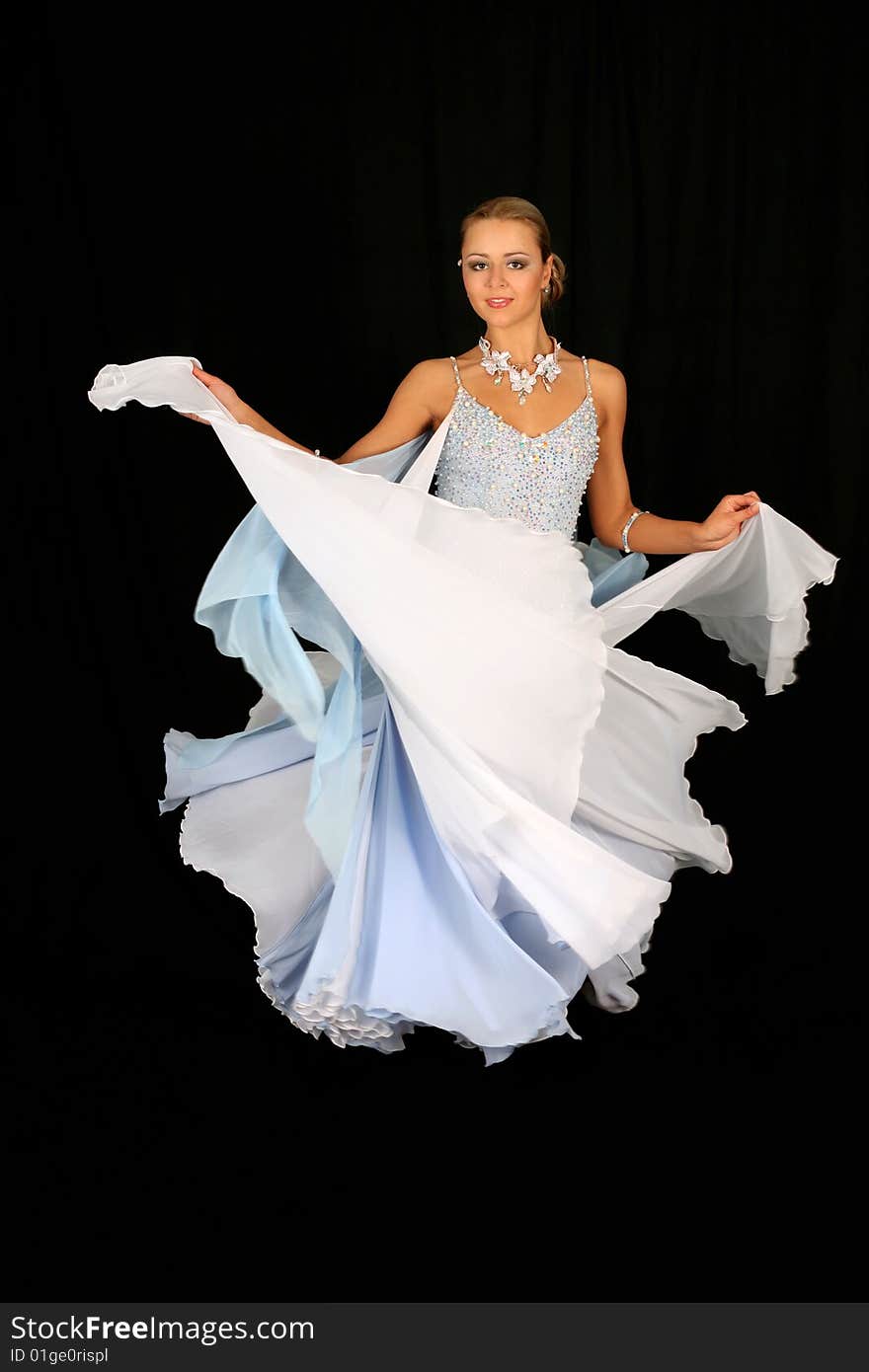 Blonde in dance in classical blue-white dress against black background