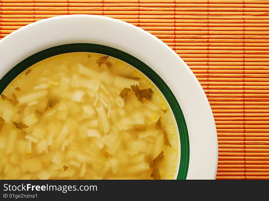 Plate with soup on yellow bamboo mat