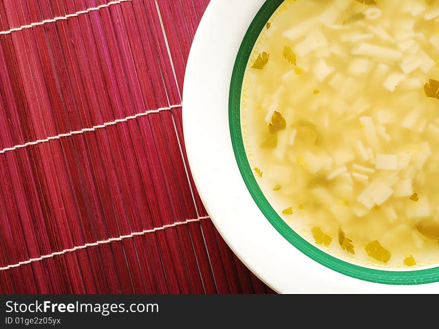 Plate with soup over red bamboo mat