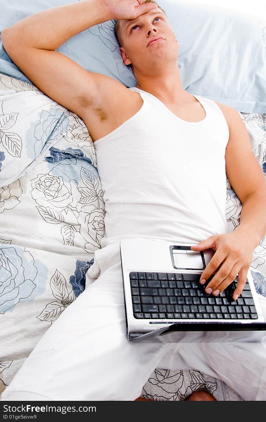 Man resting at his home with laptop and looking upwards in bed. Man resting at his home with laptop and looking upwards in bed