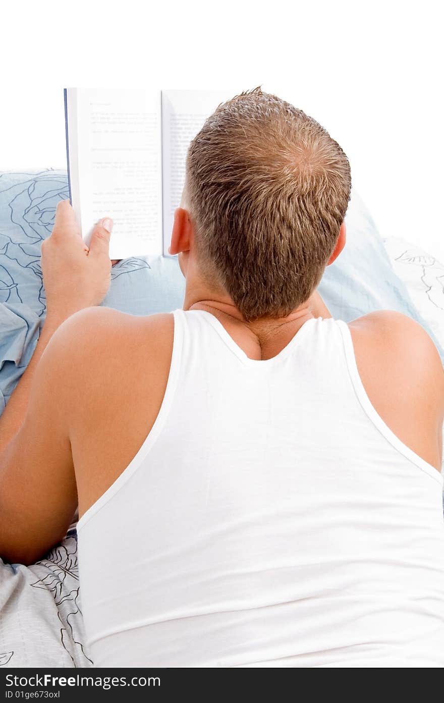 Man reading book while resting on matress bed