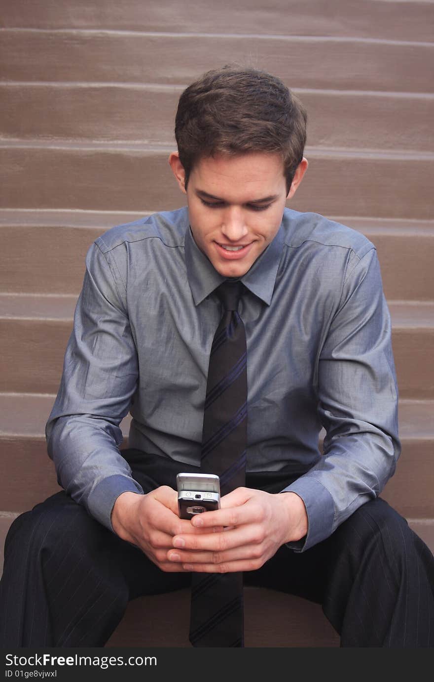 Business Man checking messages on phone sitting down on steps